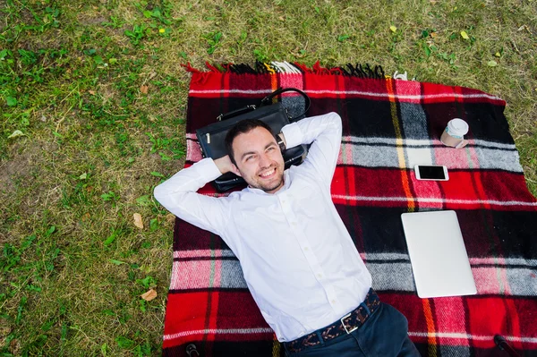 Счастливый молодой человек с ноутбуком отдыхает на траве, вид сверху — стоковое фото