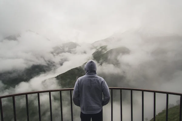 Vista de trás de um homem em pé no ponto de vista olhando para a bela paisagem com montanhas nebulosas na distância — Fotografia de Stock