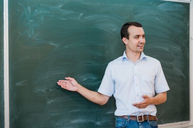 Genç erkek öğretmen boş yazı tahtası üzerine gelip konuşmak