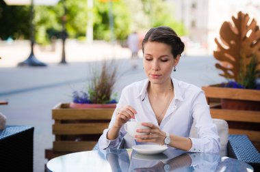 Modern genç kadın bir kafede oturan ve onu saatler arayan birini bekliyor