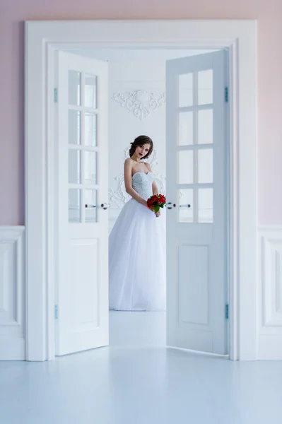 Fashion photo of a beautiful bride in the light room next to the doors — Stock Photo, Image