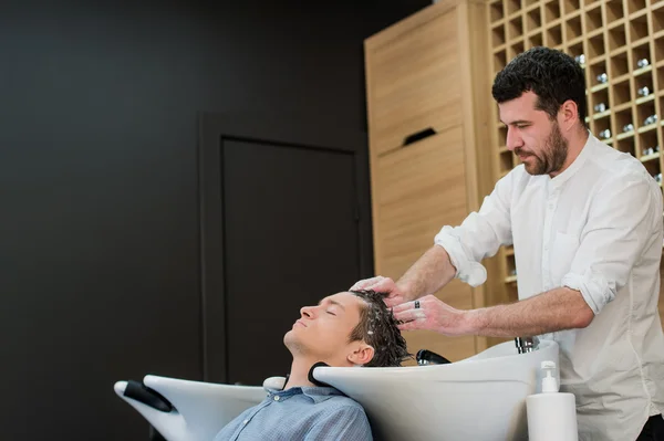 Jovem no salão de cabeleireiro recebendo seu cabelo lavado — Fotografia de Stock