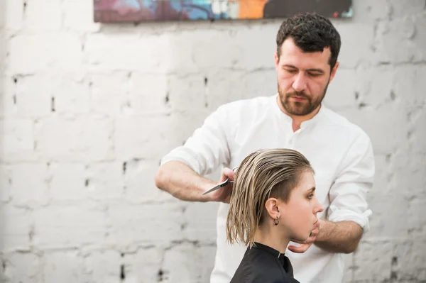 Kadeřník zastřihne vlasy s nůžkami na korunu hezký spokojeného klienta v profesionální kadeřnický salon — Stock fotografie