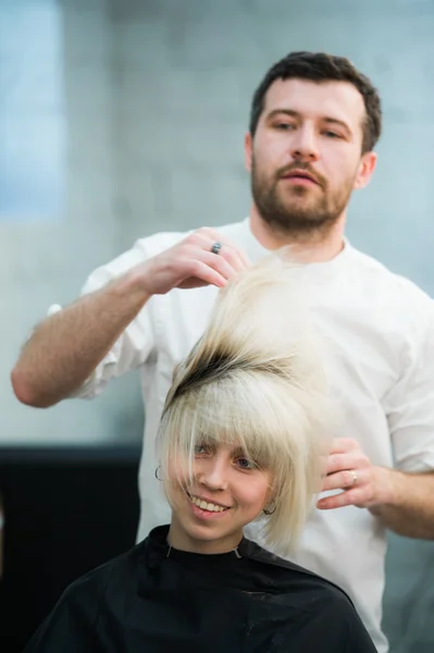 Cabeleireiro masculino coloca o cabelo das mulheres em um salão de cabeleireiro — Fotografia de Stock