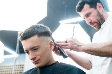 Profesyonel şekillendirme. Yan görünümü genç adamın saçını tıraş ile Kuaför tarafından berber dükkanında almak kadar kapatın