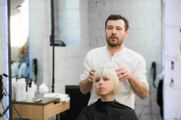 Cabeleireiro masculino coloca o cabelo das mulheres em um salão de cabeleireiro — Fotografia de Stock