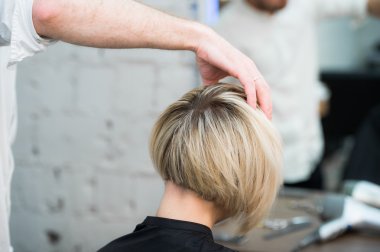 Kuaför Salonu Kuaför onu yeni saç kesimi kontrol süre aynaya bakarak sandalyede oturan kadın teen genç kız closeup arkadan görünüm