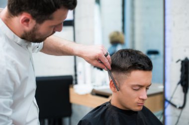 Saç kesimi salonu sahip siyah saçlı yakışıklı adam portresi. Kuaför holding tarak ve makas.