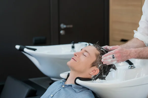 Close-up de um jovem tendo seu cabelo lavado no salão de cabeleireiro — Fotografia de Stock