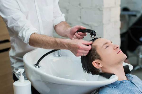 Cabeleireiro Cabeleireiro Lavar o cabelo do cliente - Jovem Relaxante no salão de beleza de cabeleireiro — Fotografia de Stock