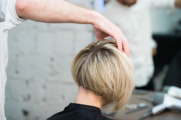 Close-up de volta vista de adolescente jovem mulher sentada na cadeira no salão de cabeleireiro olhando no espelho enquanto cabeleireiro verificando seu novo corte de cabelo — Fotografia de Stock