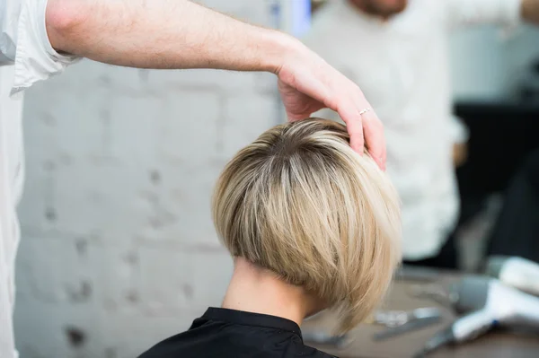 Closeup back view of teen young girl woman sitting in chair in hair salon looking in mirror while hairdresser checking her new haircut — Stock Photo, Image