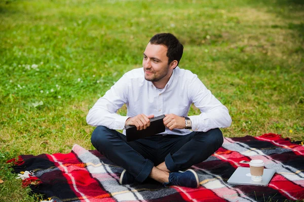 Joven hombre de negocios guapo leyendo libro acostado en el parque — Foto de Stock