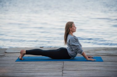 Genç kadın pratik yoga sahilde spor