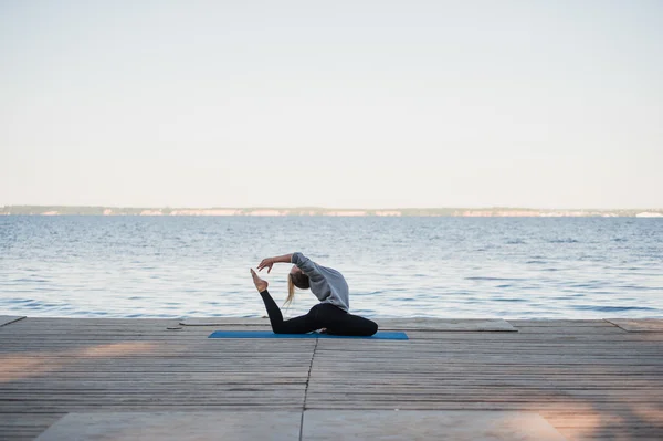 Bella donna che pratica yoga in un lago — Foto Stock