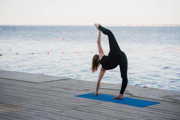 Immagine di una bella donna che fa yoga al lago — Foto Stock