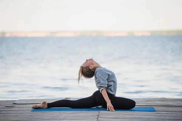 Hübsche Frau praktiziert Yoga an einem See — Stockfoto