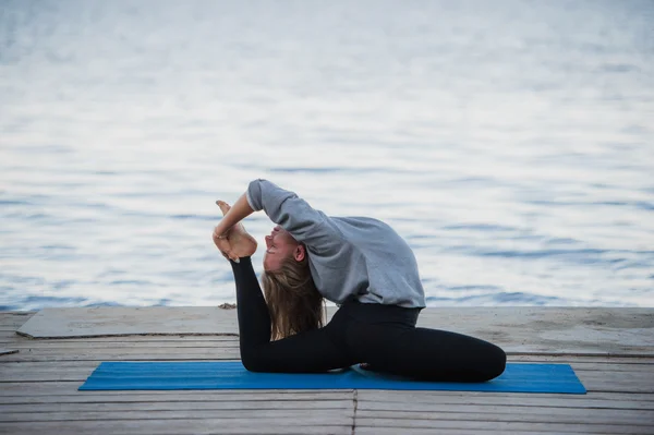 Молода спортивна жінка практикує йогу на пляжі — стокове фото