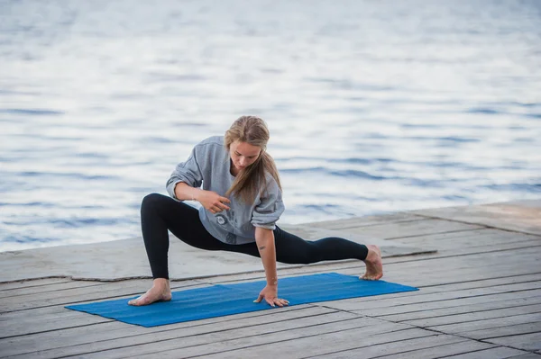 Joven deportista practicando yoga en la playa — Foto de Stock