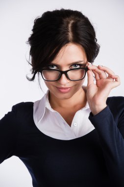 Genç iş kadını kuşkuyla beyaz arka plan üzerine onun gözlük üzerinde seyir
