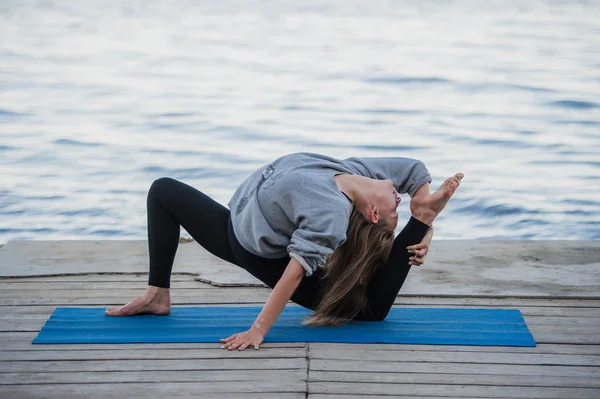 Imagem de uma mulher bonita fazendo ioga no lago — Fotografia de Stock