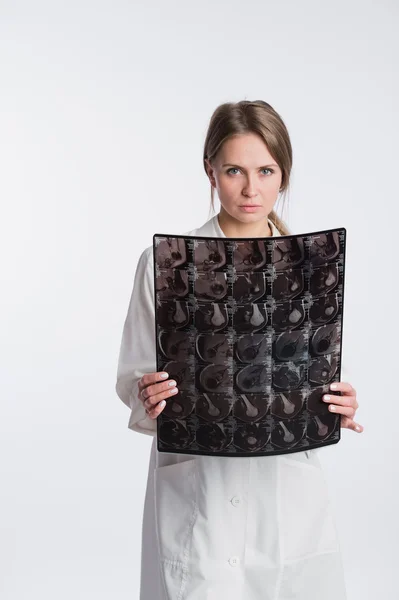 Retrato de doctora reflexiva con el uniforme blanco mirando la imagen de rayos X . — Foto de Stock