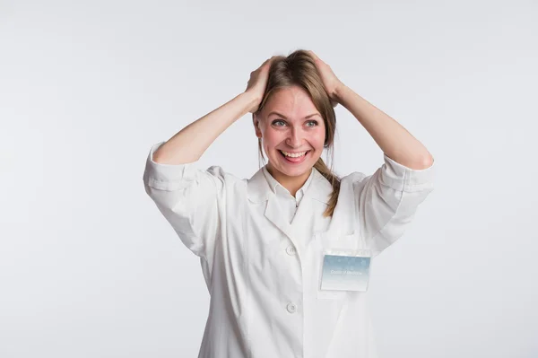 Enfermera o doctora graciosa de pie con las manos en la cabeza y la lengua colgando — Foto de Stock