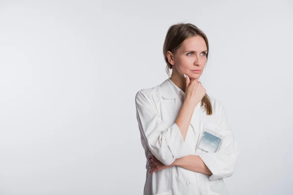 Meditada, Doctora joven mirando hacia otro lado aislada sobre fondo blanco — Foto de Stock