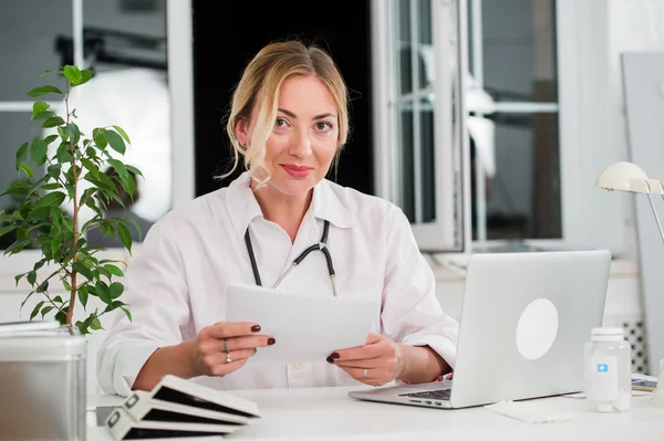 Médico femenino adulto medio leyendo documentos en el escritorio del consultorio — Foto de Stock