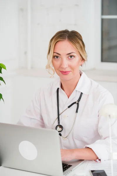 Retrato de la joven y feliz doctora trabajando en la computadora en su oficina — Foto de Stock