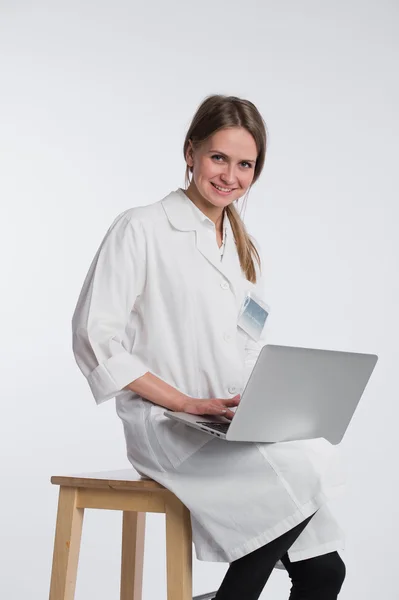 Médico sonriente trabajando en su portátil sobre un fondo blanco — Foto de Stock