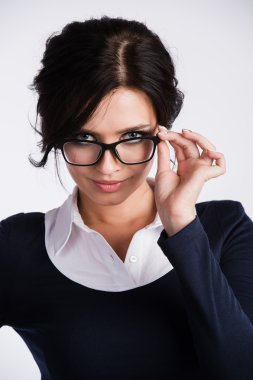 Genç iş kadını kuşkuyla beyaz arka plan üzerine onun gözlük üzerinde seyir