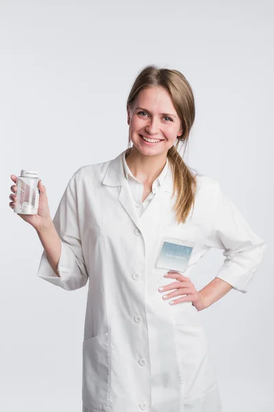 Joven doctora sonriente que presenta un frasco blanco sin etiqueta o receptora de píldoras — Foto de Stock