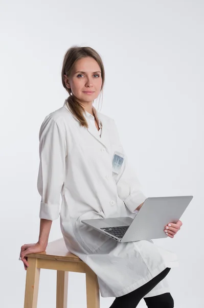 Médico sonriente trabajando en su portátil sobre un fondo blanco — Foto de Stock