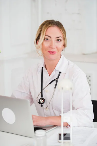 Retrato de la joven y feliz doctora trabajando en la computadora en su oficina — Foto de Stock