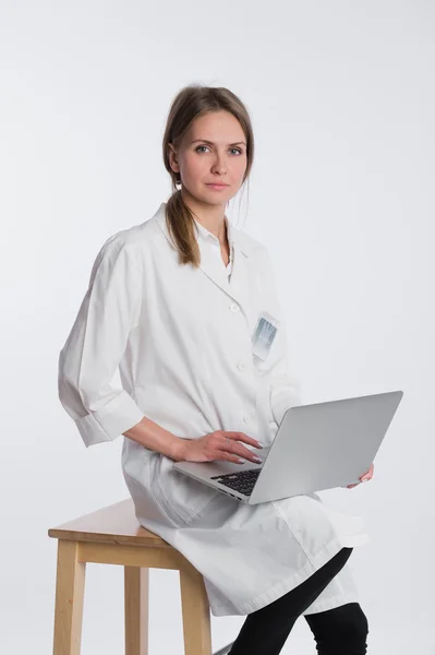 Médico sonriente trabajando en su portátil sobre un fondo blanco — Foto de Stock