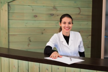Receptrion kadın gülümsüyor ve spa ya da modern klinik sanal ziyaretçi ağırlıyor. Anlaşma senin elinde kağıtlarla.