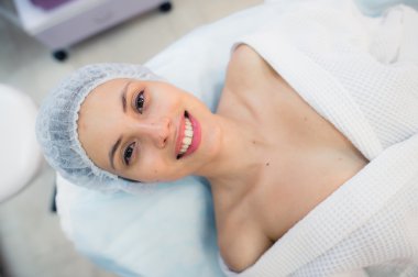 Üstten Görünüm hastane veya klinik yatakta yatan güzel genç kadının yüz cilt tedavisi için hazırlanıyor