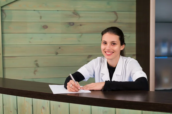 Bayan resepsiyonist hastaya dişçi klinikte form açıklayan portresi