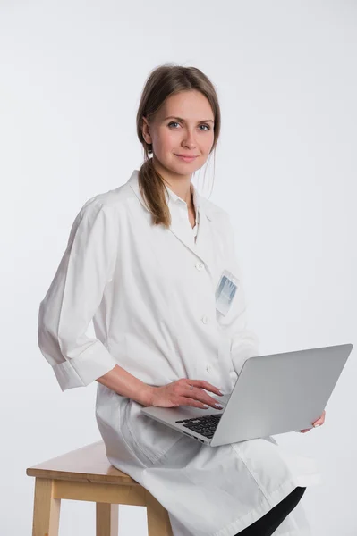 Médico sonriente trabajando en su portátil sobre un fondo blanco — Foto de Stock