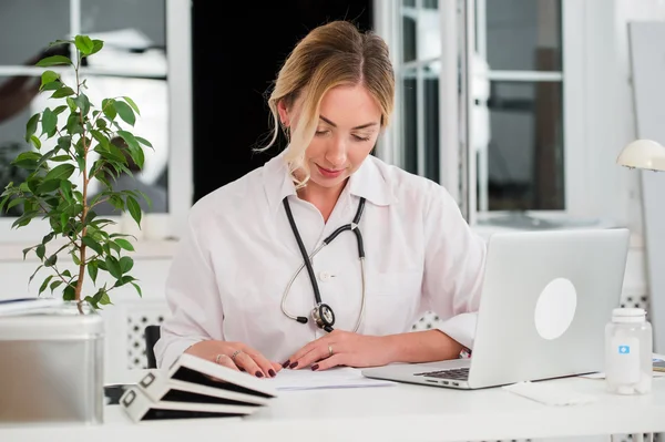 Médico femenino adulto medio leyendo documentos en el escritorio del consultorio — Foto de Stock