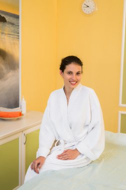 Bir Spa Masaj için bekliyor beyaz havlu kumaş bornoz giymiş güzel genç kadın.