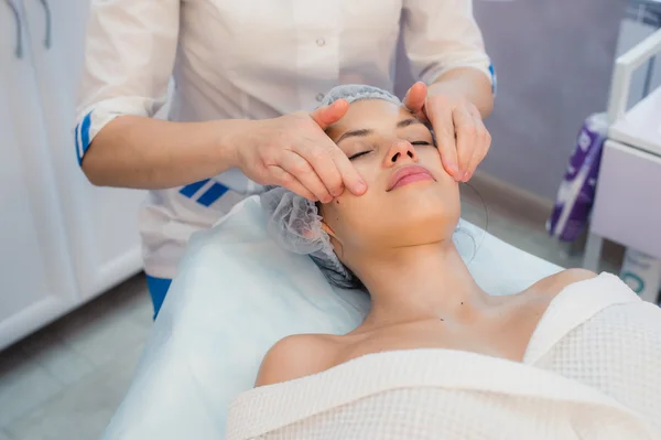 Hermosa joven mujer relajante con masaje facial en el spa de belleza — Foto de Stock