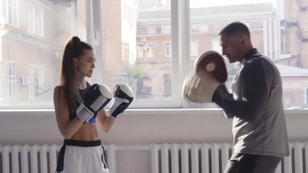 Mulher boxeadora praticando hits com seu personal trainer em um estúdio de boxe. — Vídeo de Stock