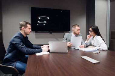 İş adamları toplantı odasında dizüstü bilgisayarlarıyla birlikte çalışıyorlar.