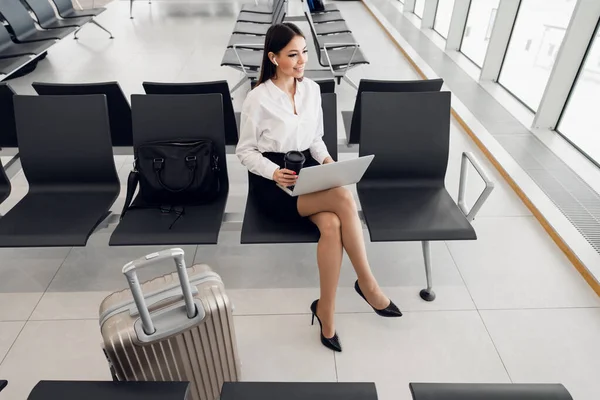 Joven mujer de negocios con estilo que trabaja con su computadora portátil en el aeropuerto —  Fotos de Stock