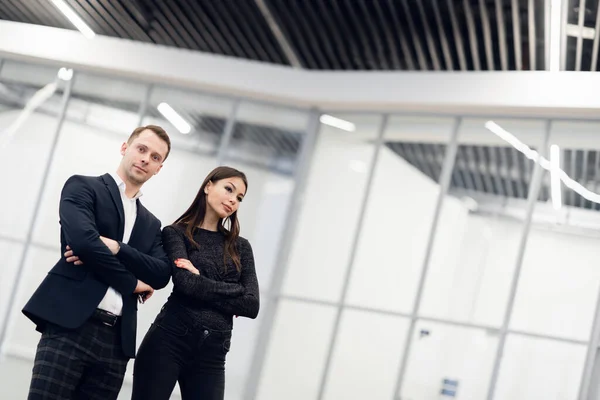 A business man and woman standing back to back with smiles on their faces — Stock Photo, Image