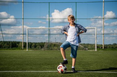 Çocuk yaz sahasında futbol oynuyor.