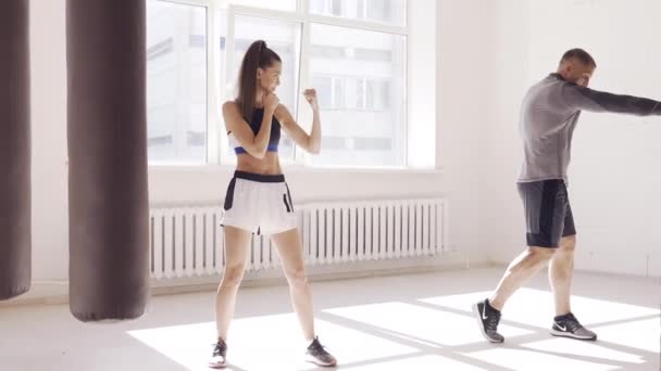 Ein erfahrener Trainer bringt einem jungen Mädchen in der Boxhalle die Technik der Schläge bei — Stockvideo