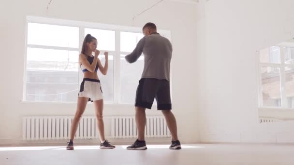 Jolie fille apprend les techniques de kickboxing dans la salle de gym avec un entraîneur expérimenté — Video